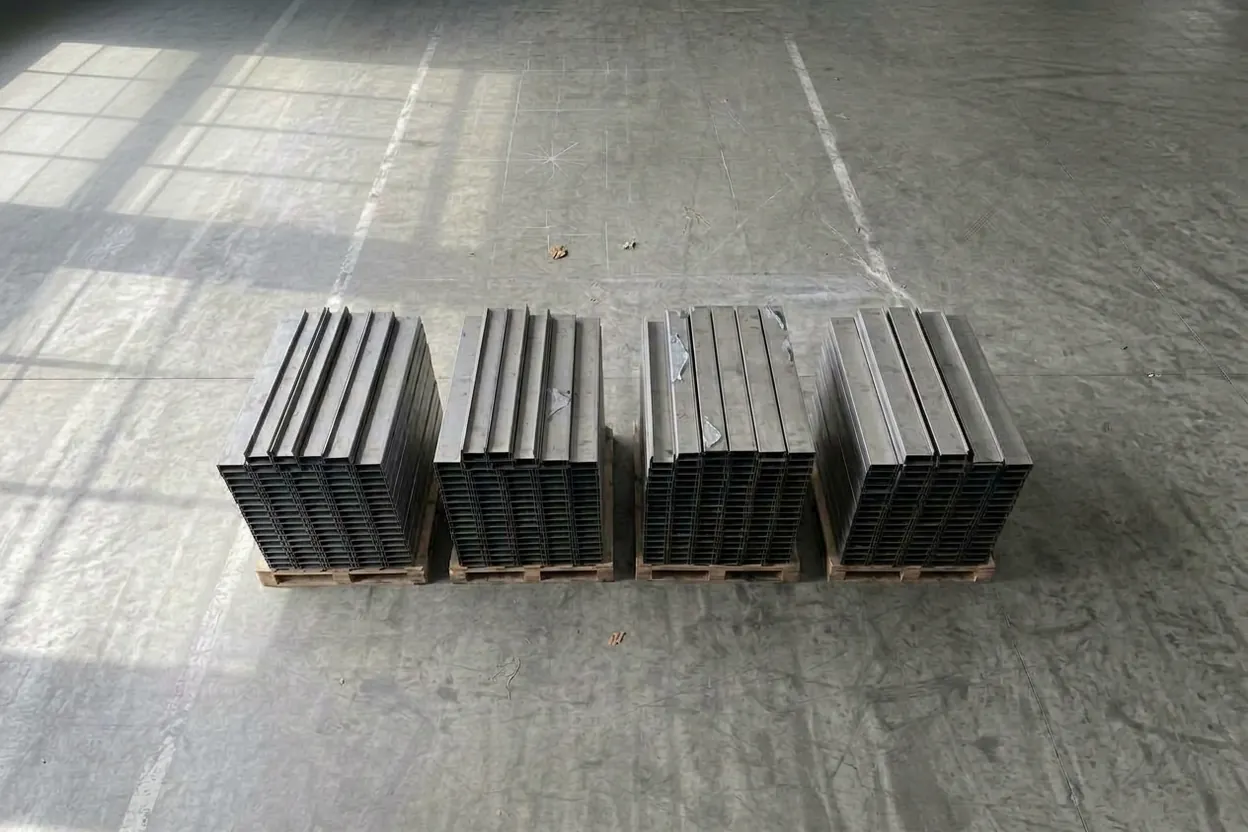 Four pallets of bent stainless U-channels, stacked and ready to ship