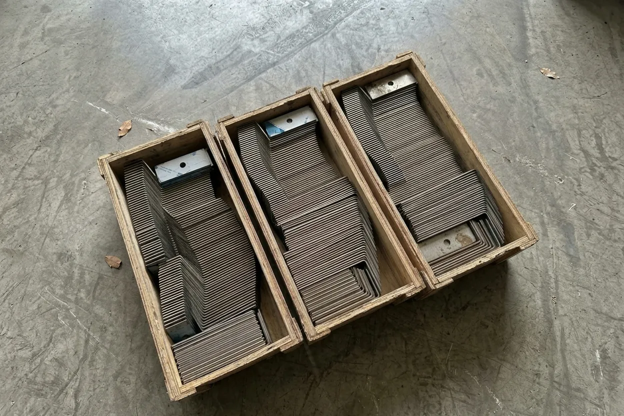 Three crates of nested stainless L-brackets, about five hundred bent parts