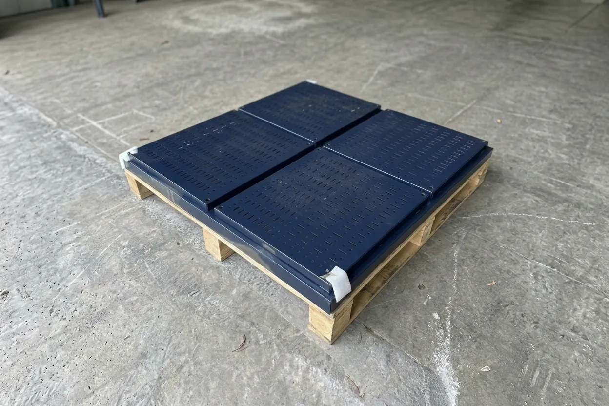 Navy powder-coated steel panels with laser-cut slots, on a pallet
