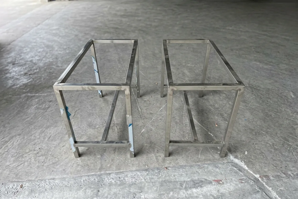 Two welded stainless table frames standing side by side